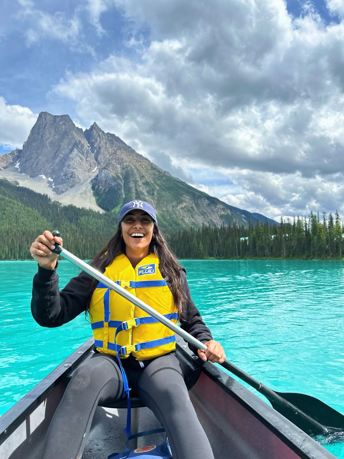 Radhika laughing in a canoe on a turquoise mountain lake