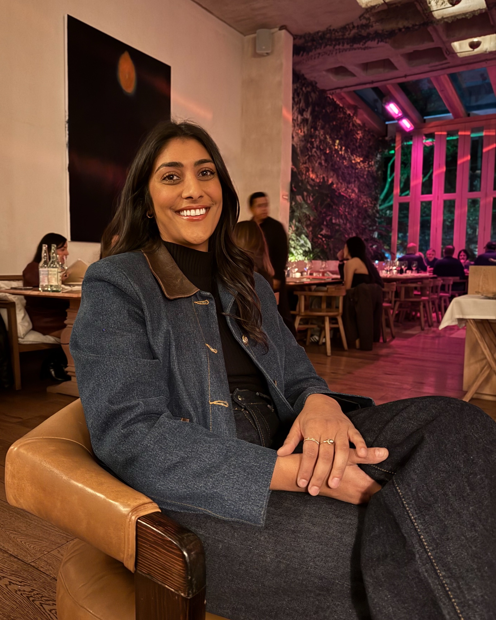 Radhika smiling in a leather chair at a restaurant